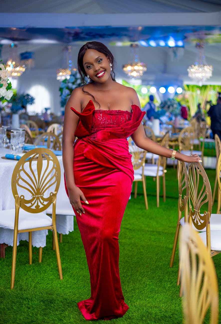 Stunning woman in a red dress posing elegantly at an upscale wedding reception in Uganda.