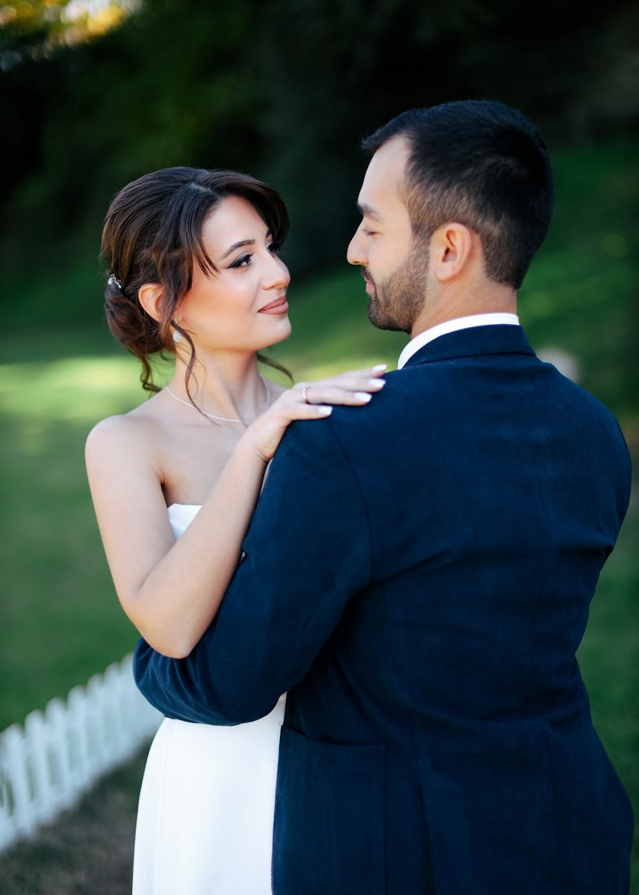 Bride and groom embracing outdoors in a romantic wedding scene.