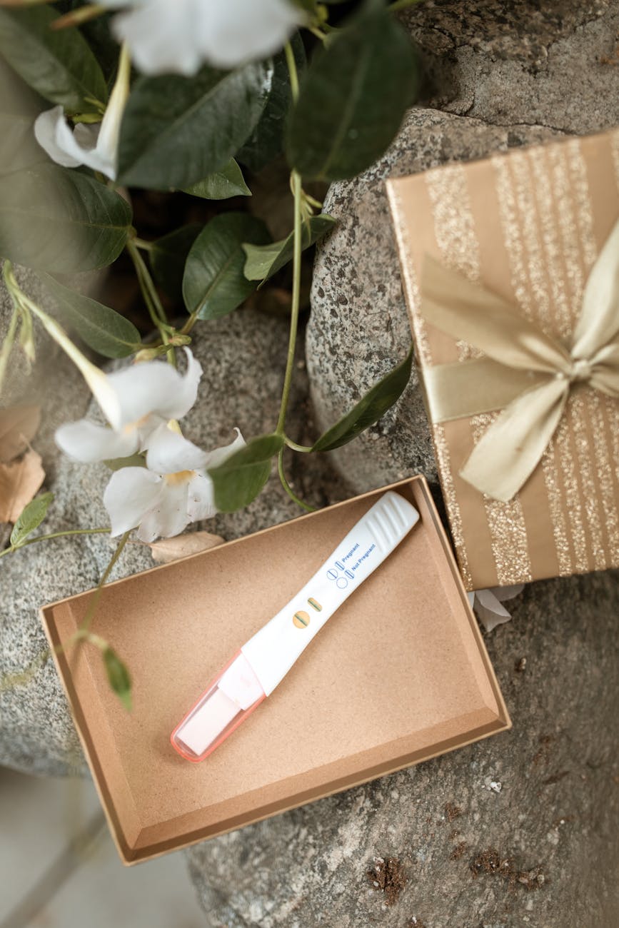 Positive pregnancy test displayed in a decorative gift box with flowers.