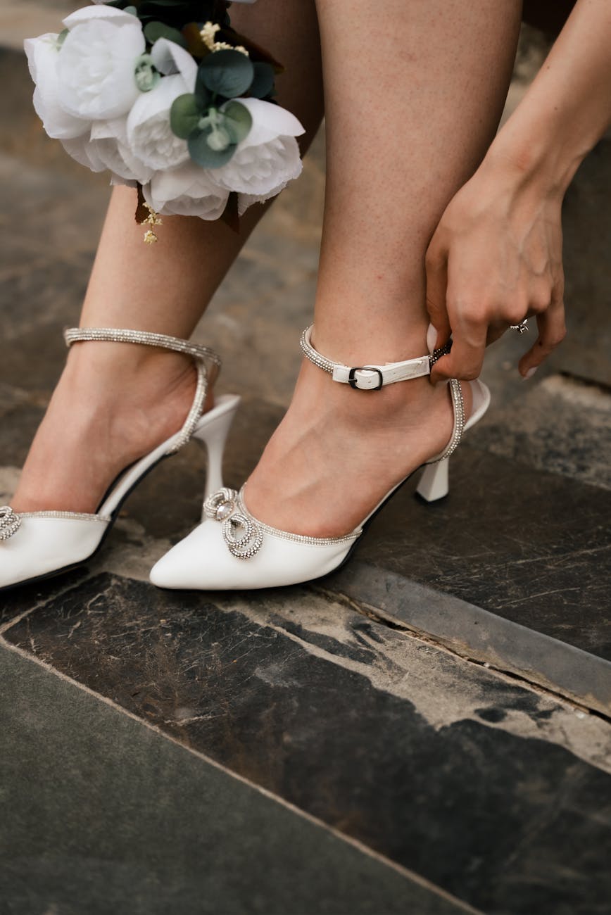 Close-up of bridal shoes and bouquet on stone steps, showcasing elegance and bridal fashion.