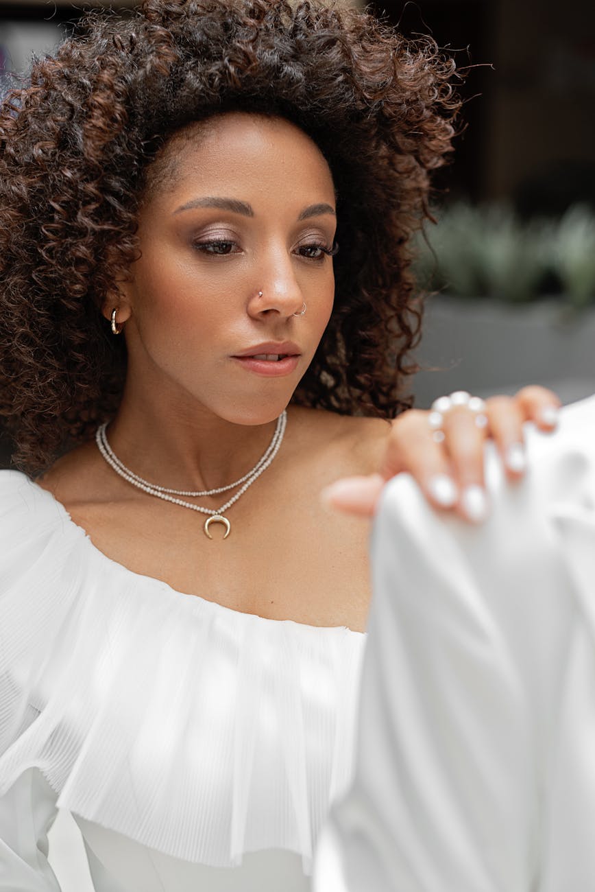 Beautiful African American bride with curly hair and a stylish nose piercing gazes thoughtfully on her wedding day.