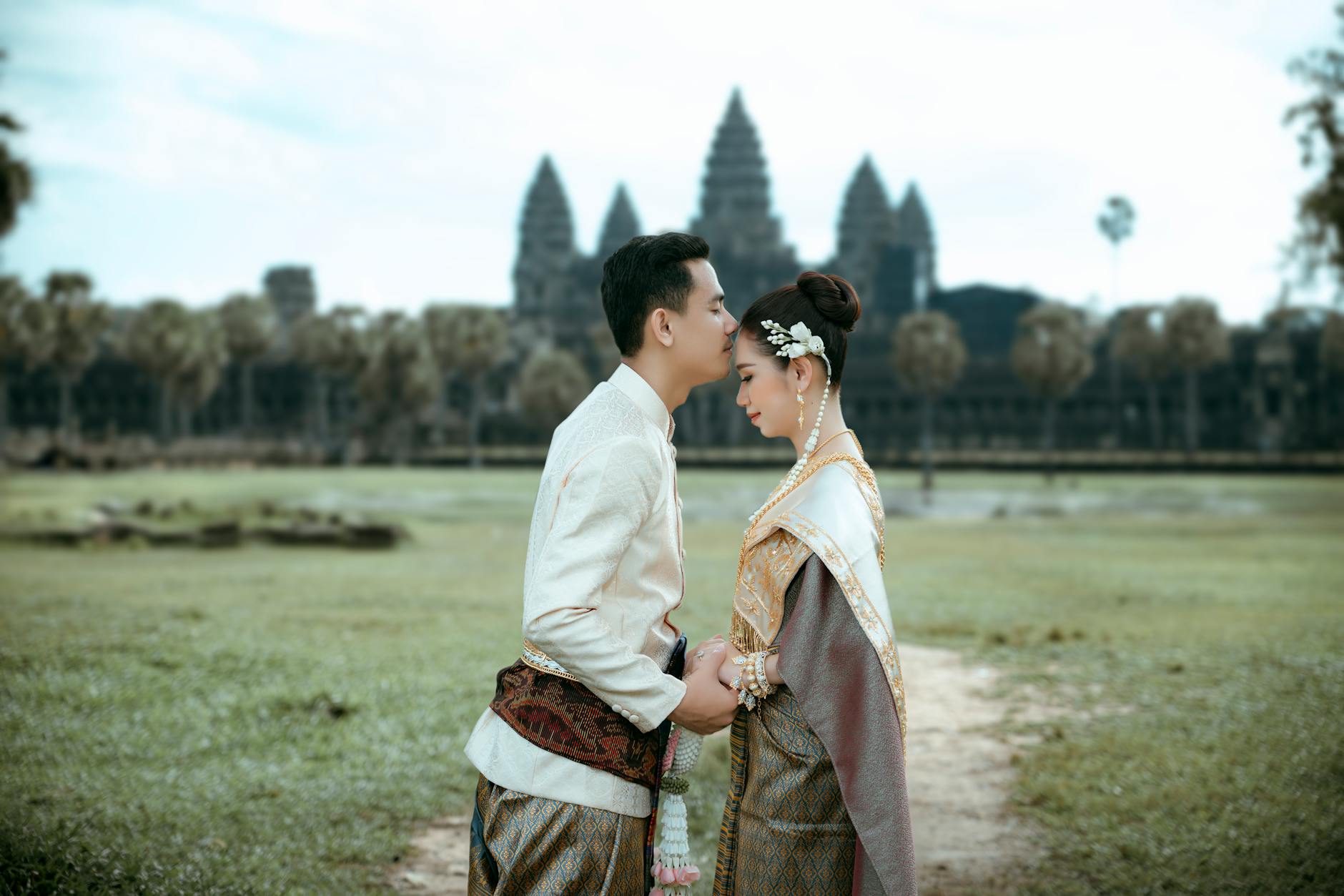 A couple in traditional Cambodian attire embracing at Angkor Wat, a symbol of timeless love.